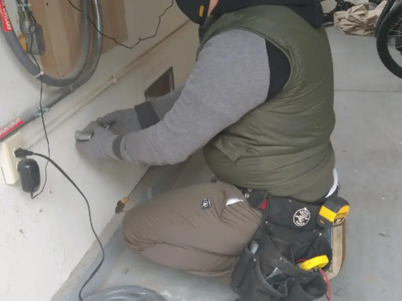 Electrician performing outlet wiring in a Williamsburg garage